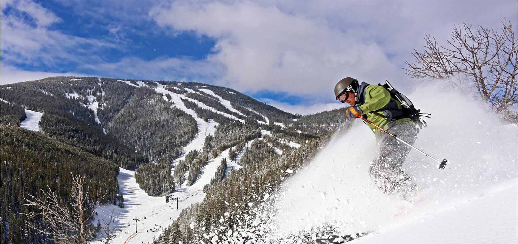 man skiing fresh snow with red lodge mountain in the background