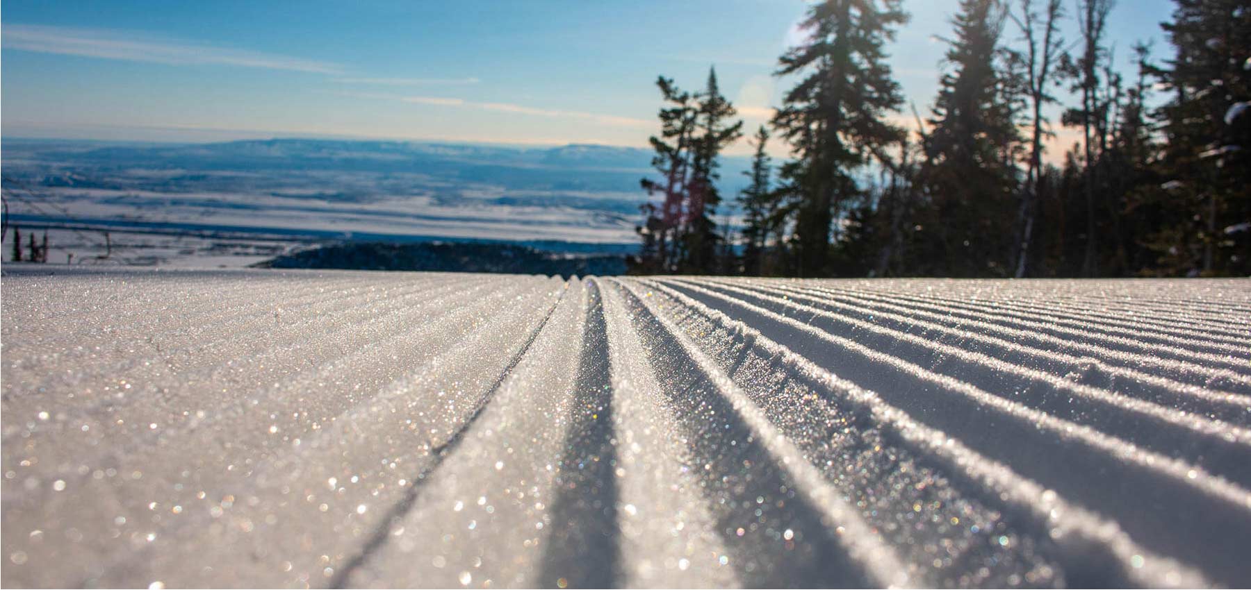 sun shines on groomed run and makes the snow sparkle