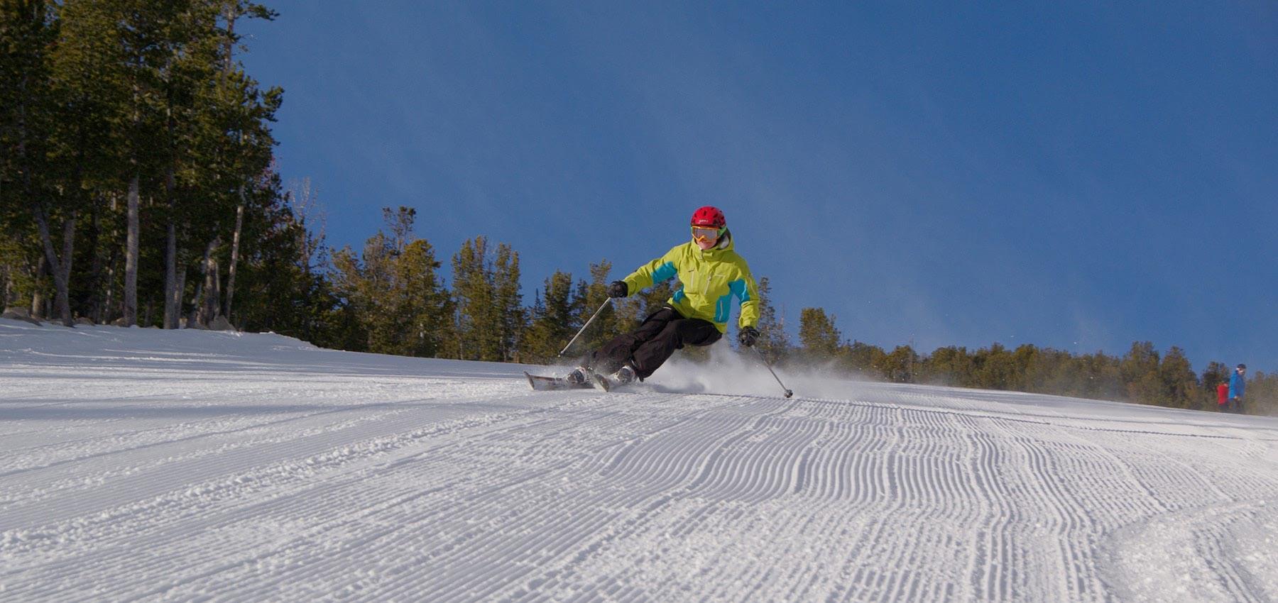 skier carving a turn on groomed run under blue sky